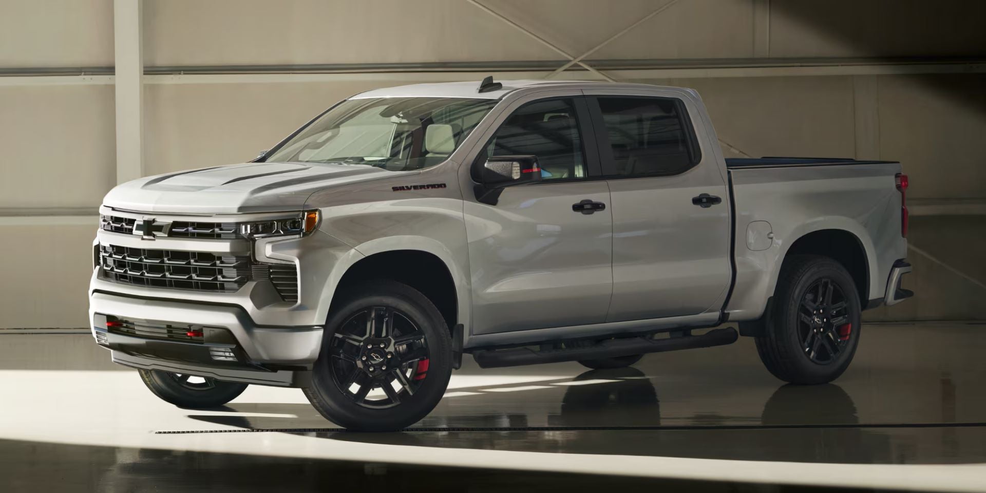 Silver pickup truck parked indoors in a bright, spacious garage, shown in a side-front view