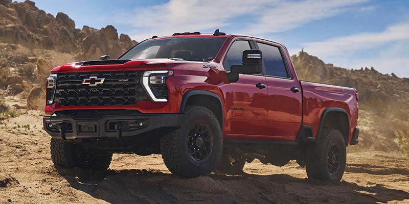 Red pickup truck driving on a rocky desert terrain